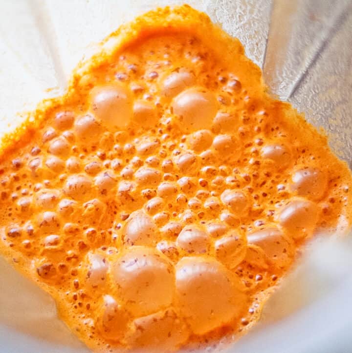 Brightly colored orange Chipotle Marinade for Chicken, Pork and Steak bubbling in a blender.
