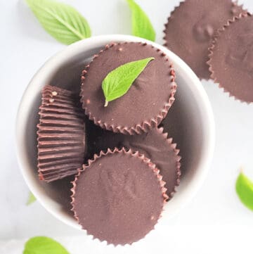 Chocolate cups filled with peppermint cream in a white bowl.