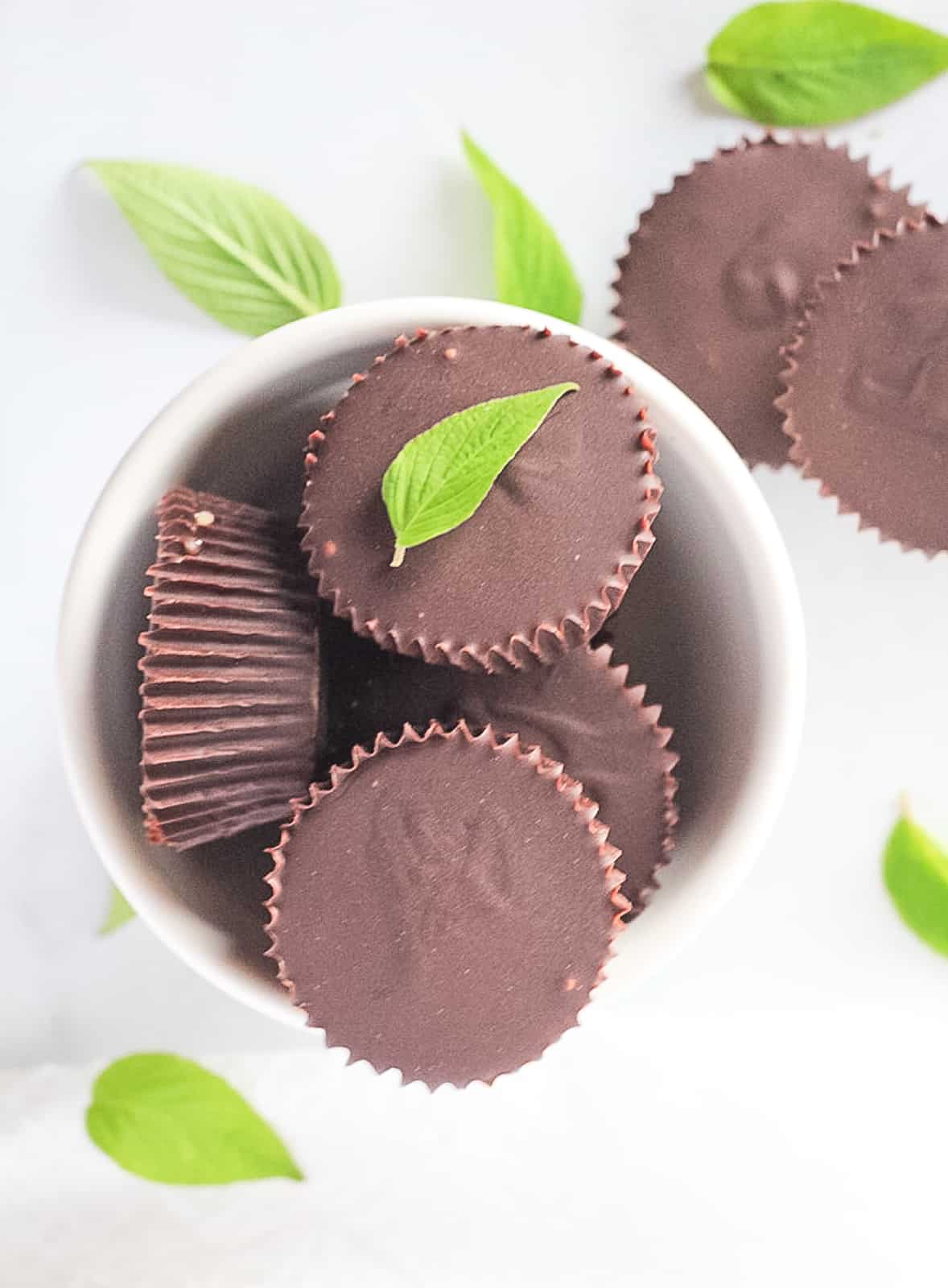Chocolate cups filled with peppermint cream in a white bowl.