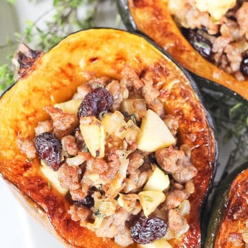Stuffed acorn squash filled with sausage, apples and cranberries surrounded by herbs.