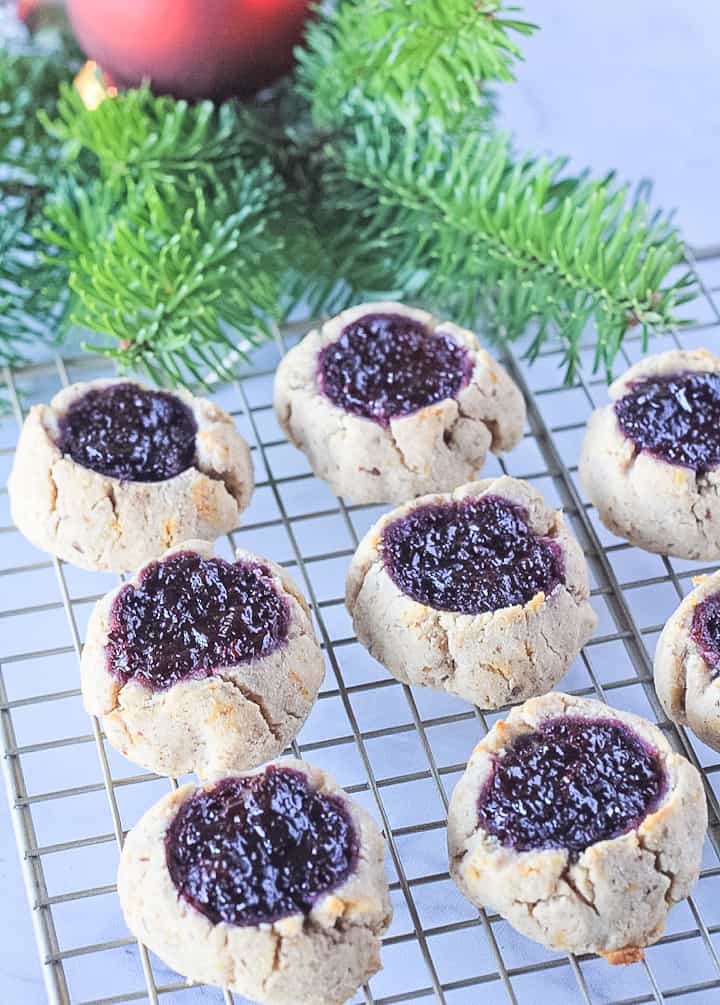 Paleo thumbprint cookies cooling on a wire rack filled with blackberry chia seed jam.