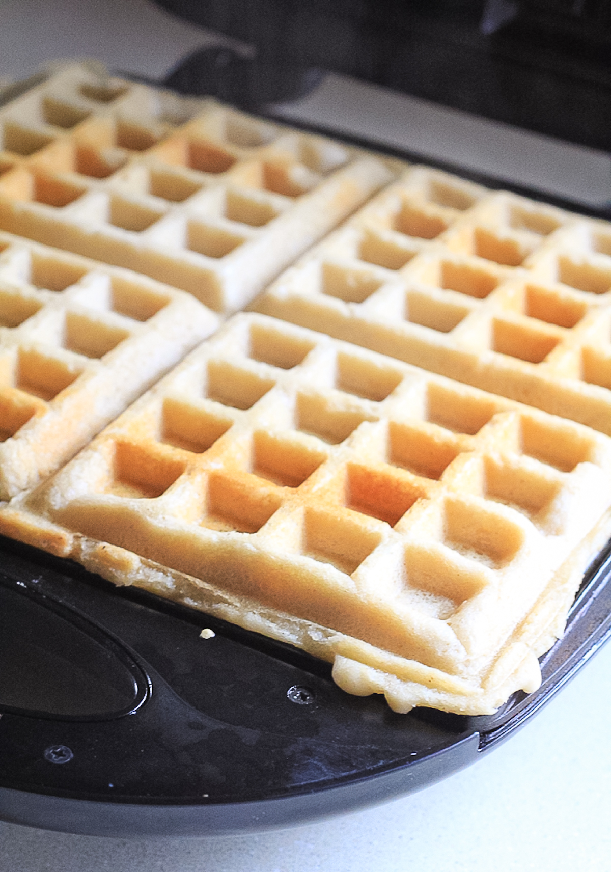 Waffles cooking in a waffle iron.