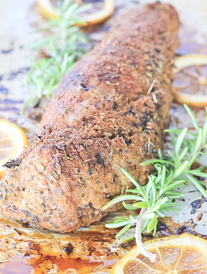Baked Pork Tenderloin just out of the oven on a sheet pan with lemon and fresh rosemary.