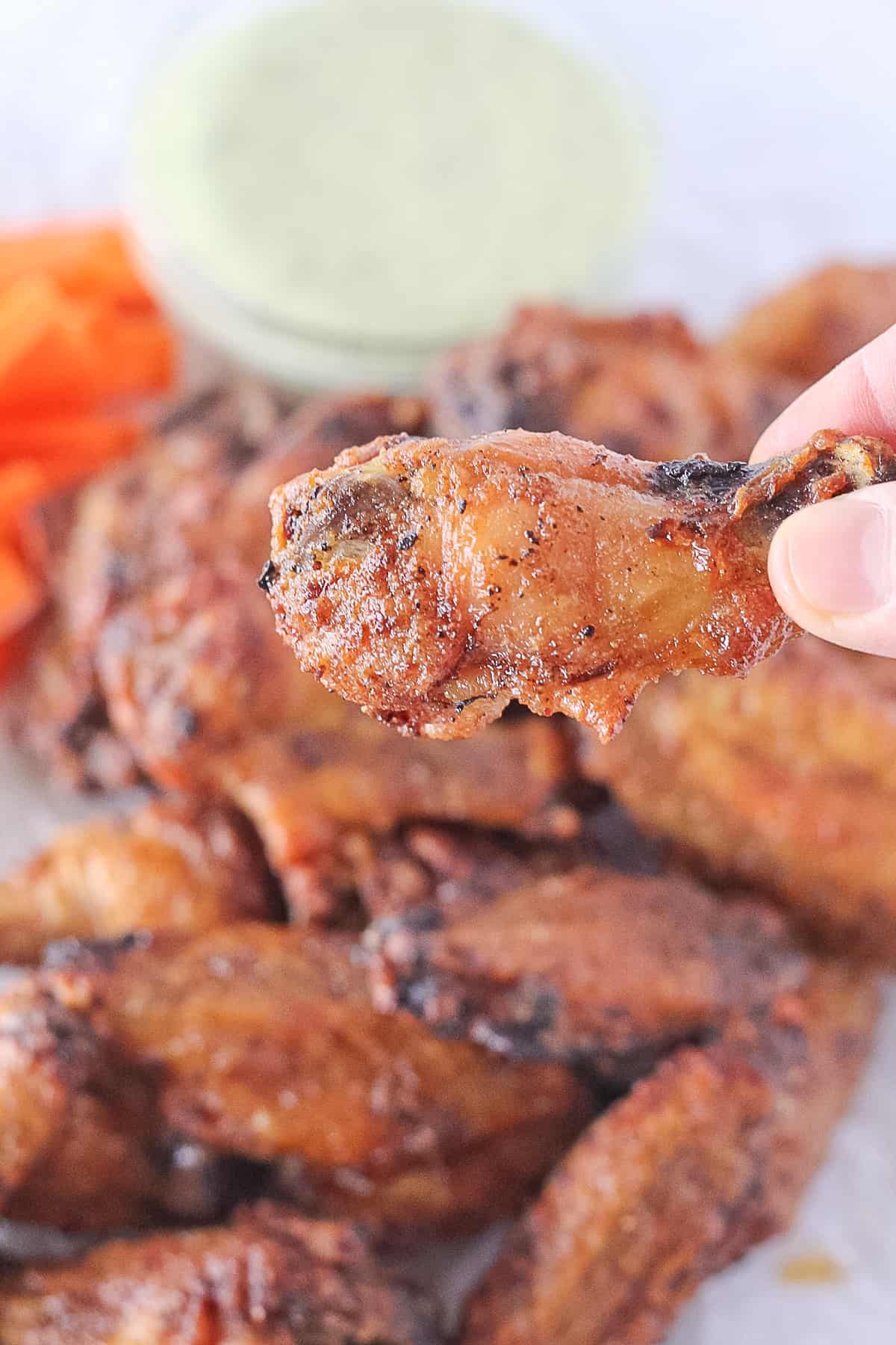 Fingers picking up one baked crispy whole30 chicken wing.