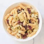 Big white bowl of summer pasta salad with artichokes and olives.