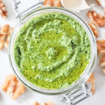 Rocket pesto in a glass jar drizzled with olive oil.