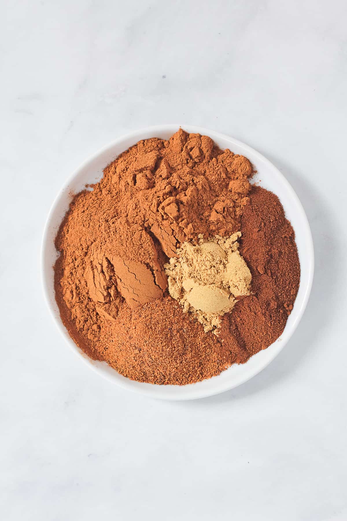 Small white plate of pumpkin pie spice ingredients.