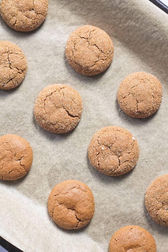 Ginger cookies baked on a parchment paper baking sheet.