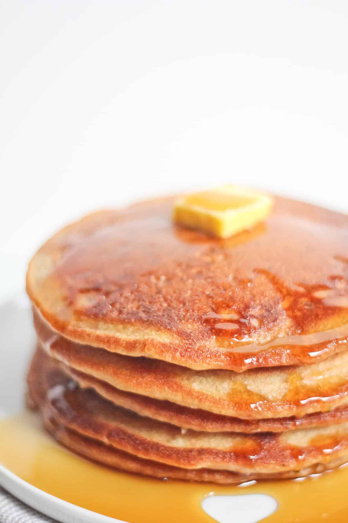 Stack of sourdough pancakes with butter and syrup on top.