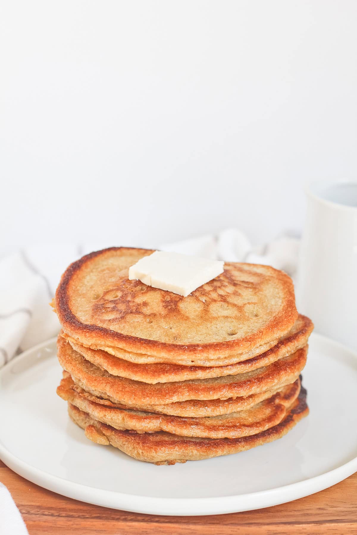 Stack on pancakes with butter on top sitting on white plate.