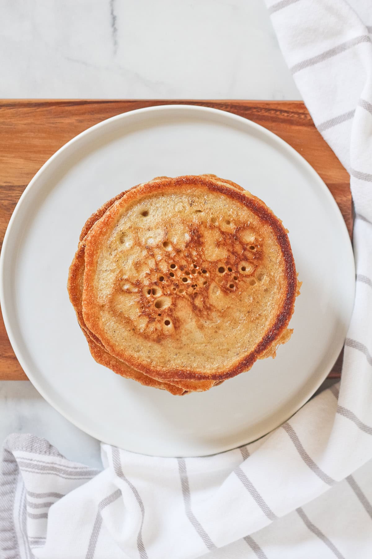 Pancakes on a white plate and wood serving board.