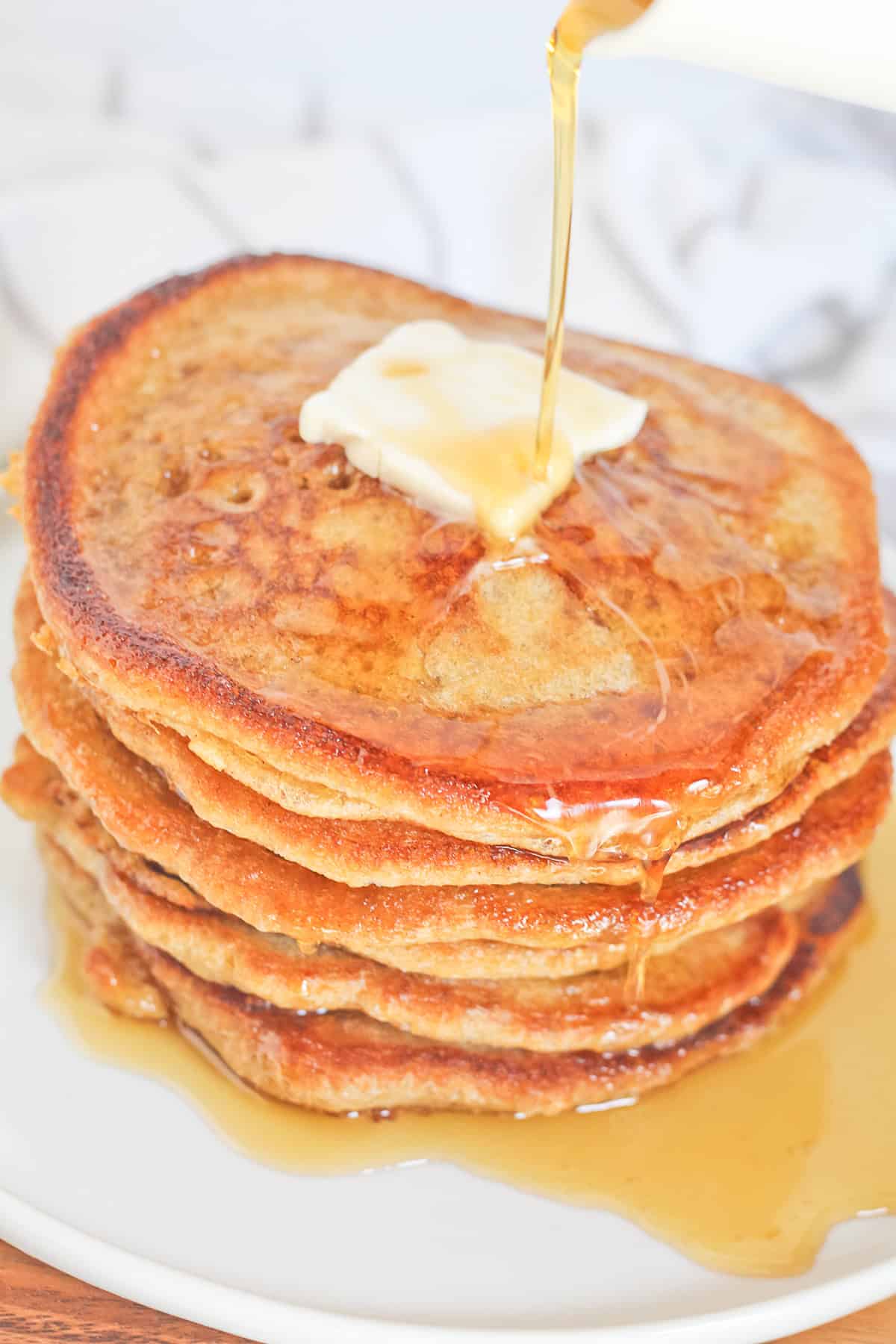 Stack of sourdough discard pancakes with syrup being poured overtop of them.