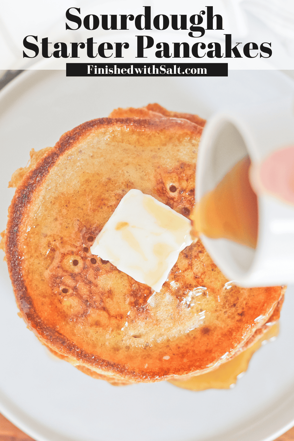 Sourdough pancakes with butter and syrup being poured overtop.