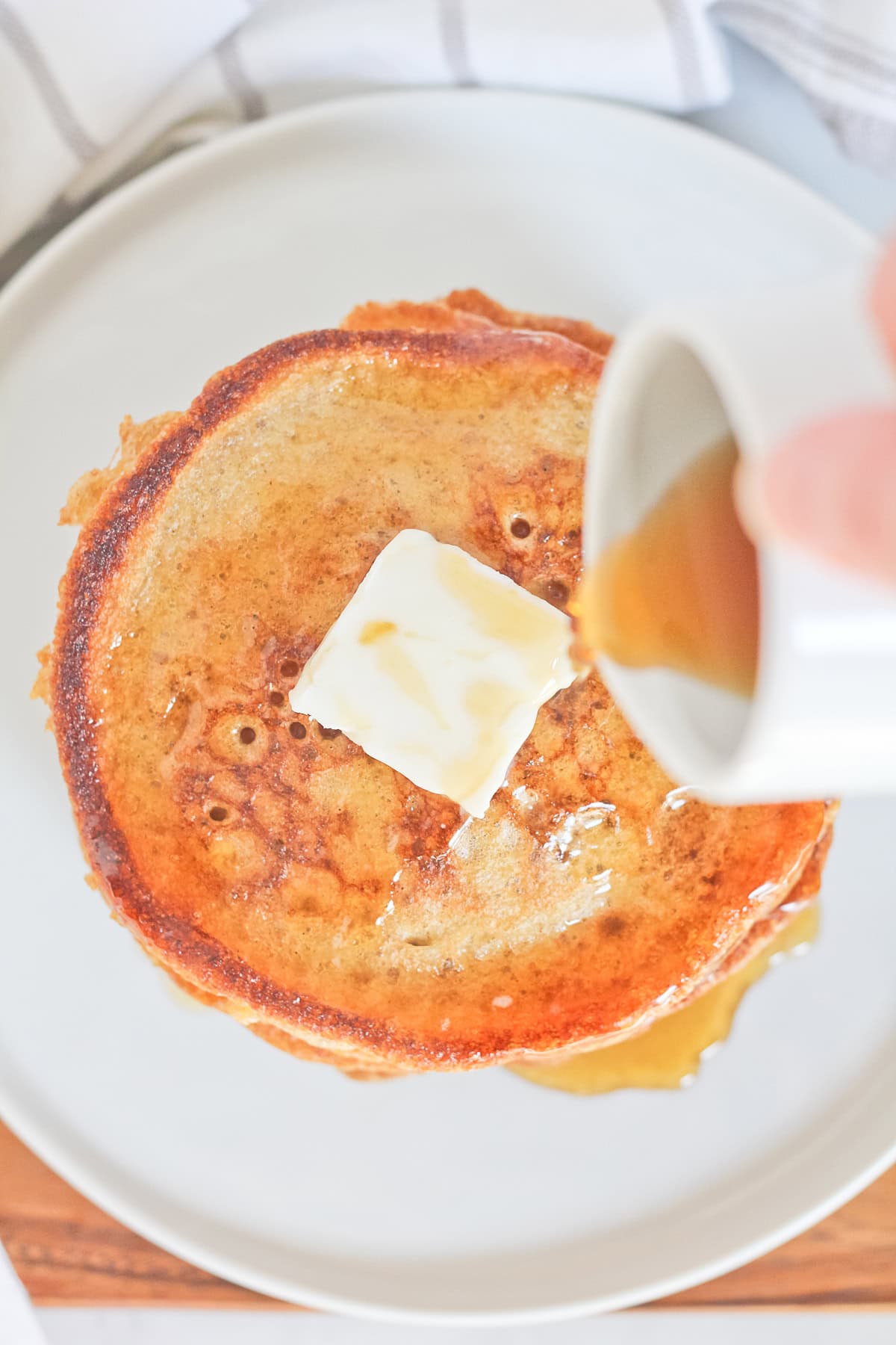 Stack of sourdough pancakes with syrup being poured overtop.